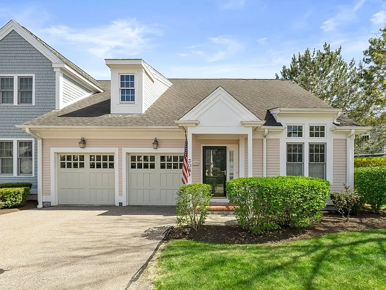 Front exterior of a Wheaton-style end unit home with two-car garage in the Great Brook 55+ community, featuring manicured landscaping.